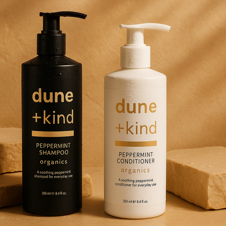 Black shampoo bottle and white conditioner bottle with 'dune + kind' branding on a beige background.