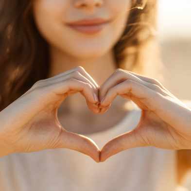 Person making a heart shape with their hands against a blurred background