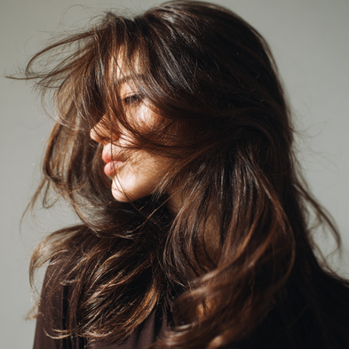 Close-up of a person with long, wavy hair against a neutral background